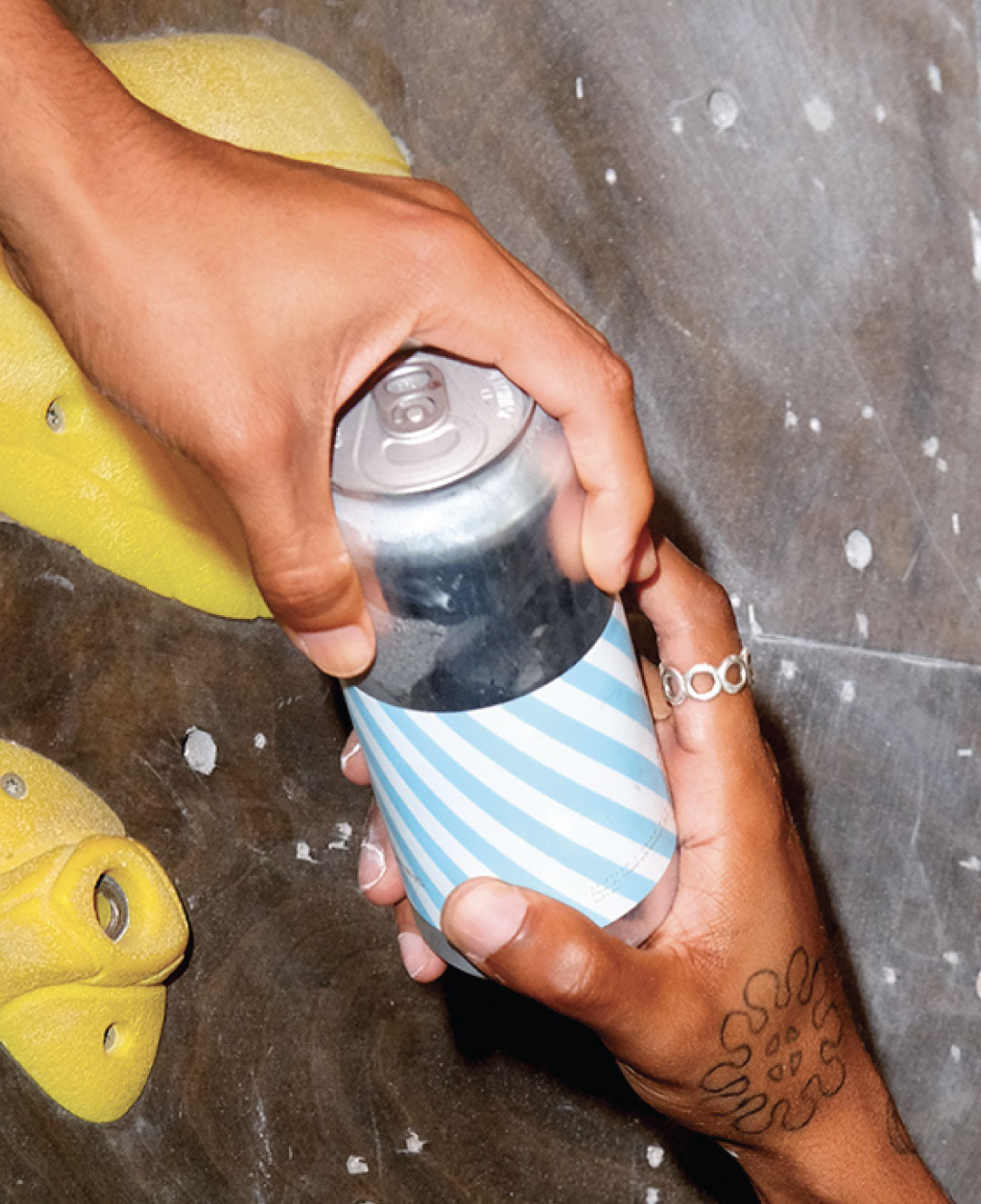 Climbers exchanging canned beverage while indoor rock climbing